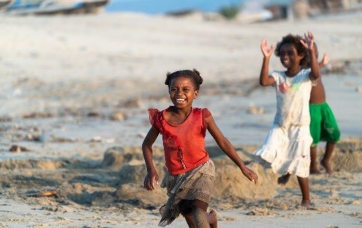 Enfants malgaches souriant et jouant sur une plage à Madagascar lors d’une rencontre locale
